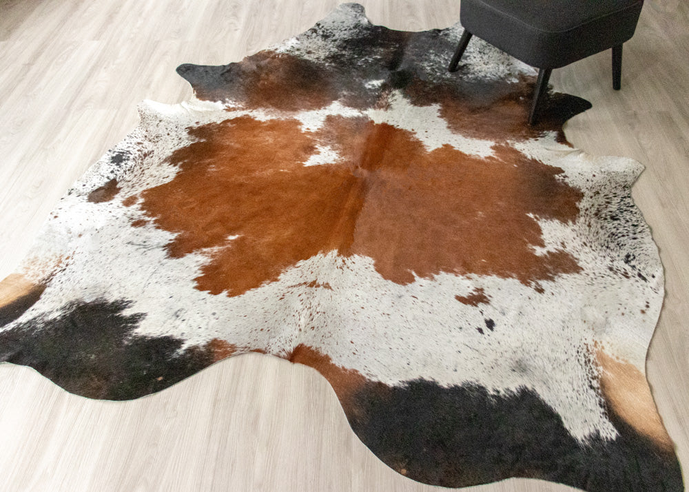 Cowhide rug with brown, black, and white pattern on a wooden floor.