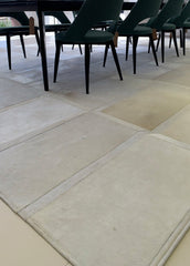 An off-white cowhide patchwork rug laid out on a tiled floor with furniture set on top of it.