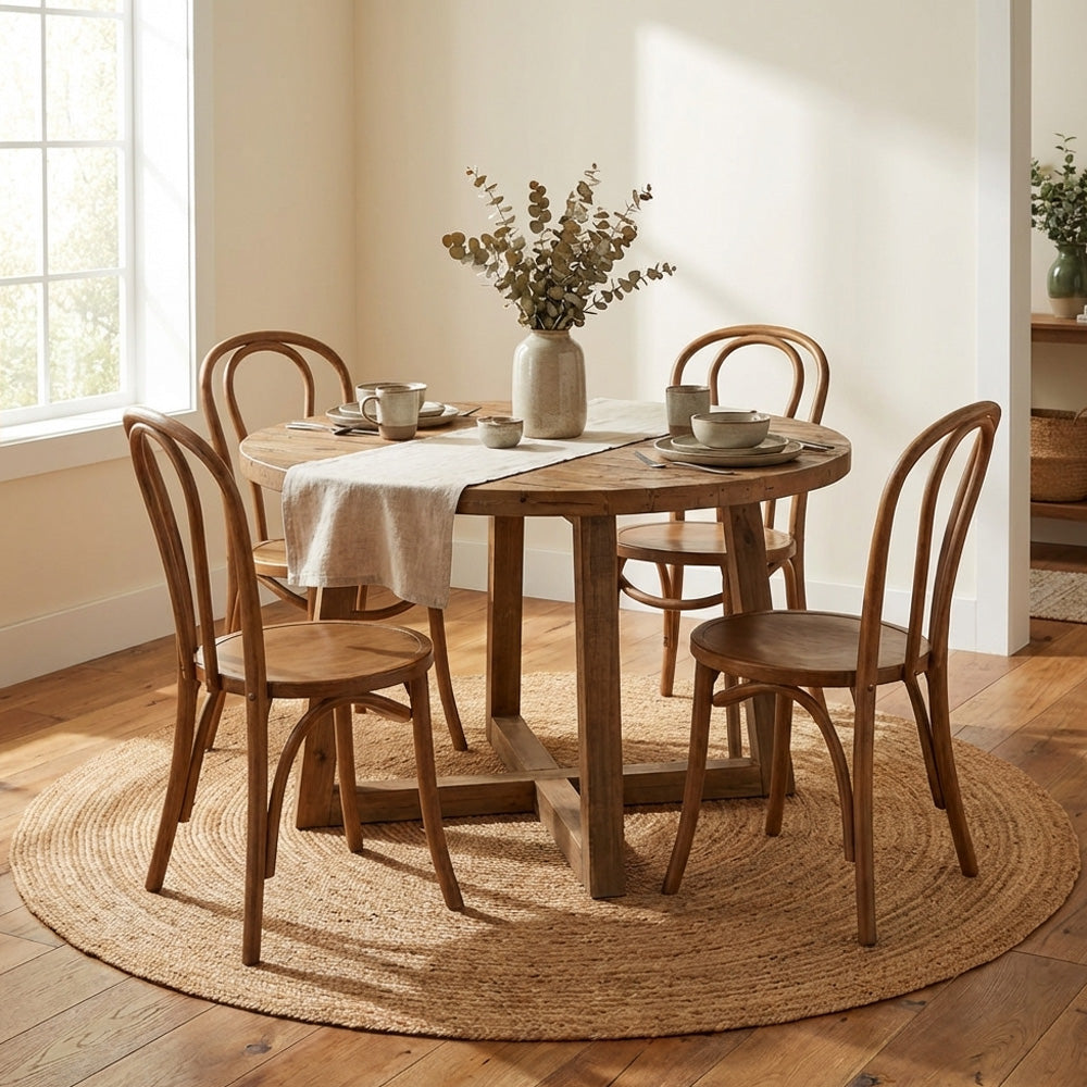 Wooden dining table with chairs in a bright room with round plain natural jute rug.