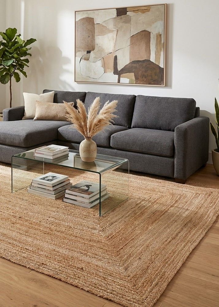 Modern living room with a gray sofa, glass coffee table, and rectangular jute rug.