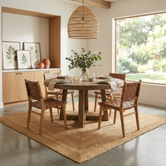 Dining room with a wooden table and chairs, a large window, and a square jute rug.