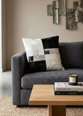 Black and white colour block cowhide patchwork cushion styled on a modern grey sofa