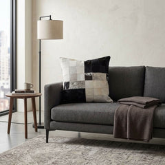 Black and white colour block cowhide cushion styled on a grey sofa in a contemporary living room