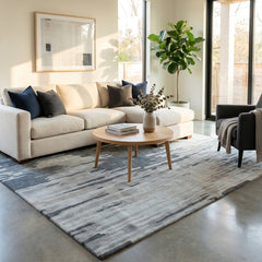 Modern living room with a beige sectional sofa, coffee table, and decorative wool rug.
