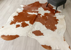 Brown and white cowhide rug on a wooden floor