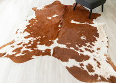 Brown and white cowhide rug on a light wooden floor.