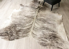 Grey and white brindle cowhide rug on a wooden floor