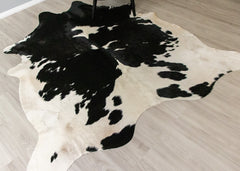 Black and white cowhide rug on a wooden floor