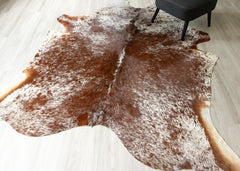 Brown and white cowhide rug on a wooden floor
