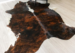 Brown and white brindle cowhide rug on a light wooden floor