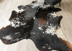 Brown and white tricolor cowhide rug on a wooden floor