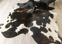 Brown and white dark brindle cowhide rug on a light wooden floor