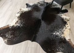 Black and brown cowhide rug on a wooden floor