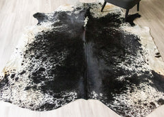 Black and white cowhide rug on a light wooden floor