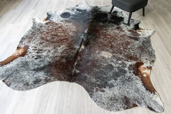 Brown and black salt peppar cowhide rug on a light wooden floor