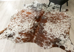 Cowhide rug with brown and white pattern on a light wooden floor.