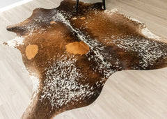 Brown and white cowhide rug on a light-colored floor