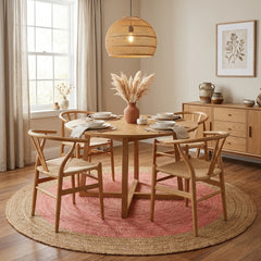 Dining room with wooden table and chairs on a pink jute rug, natural light from the window.