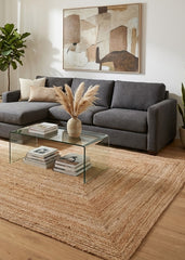 Modern living room with a gray sofa, glass coffee table, and rectangular jute rug.