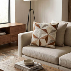 Tan and ivory faceted cowhide cushion styled on a cream sofa in a warm contemporary interior